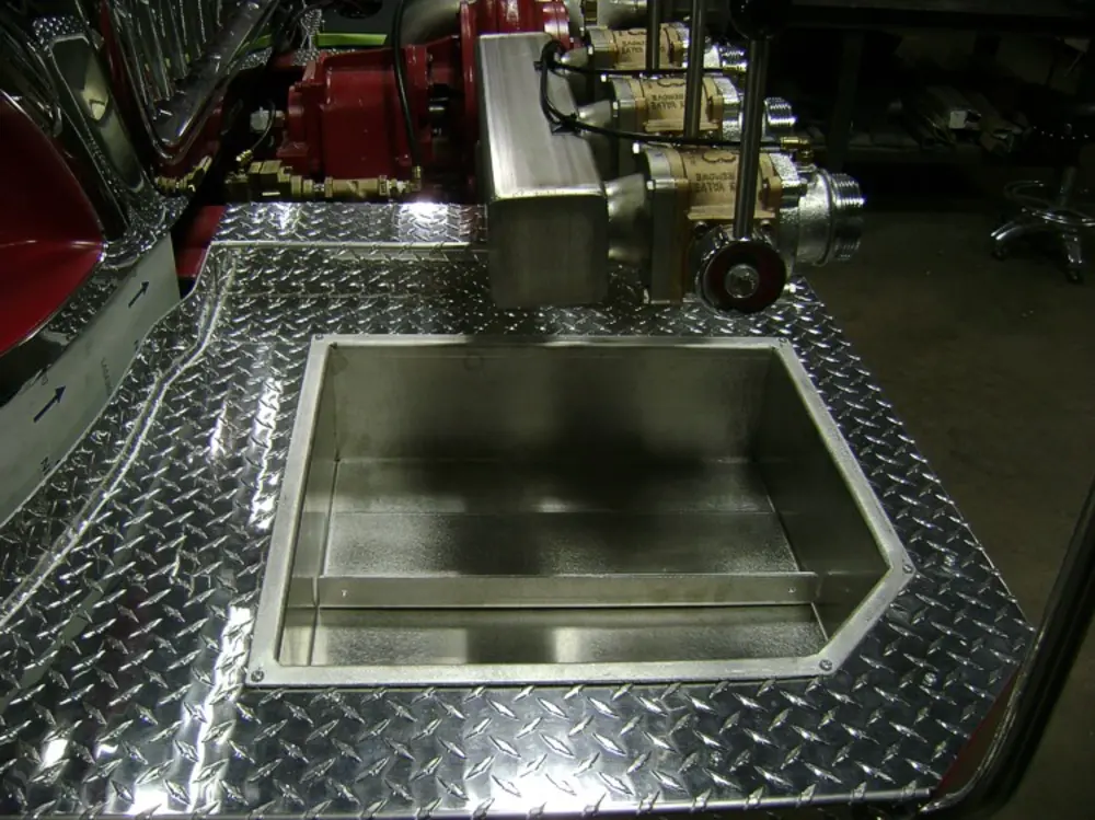 Exterior view of small fire truck showing cab, body compartments, and wheel/tire area.