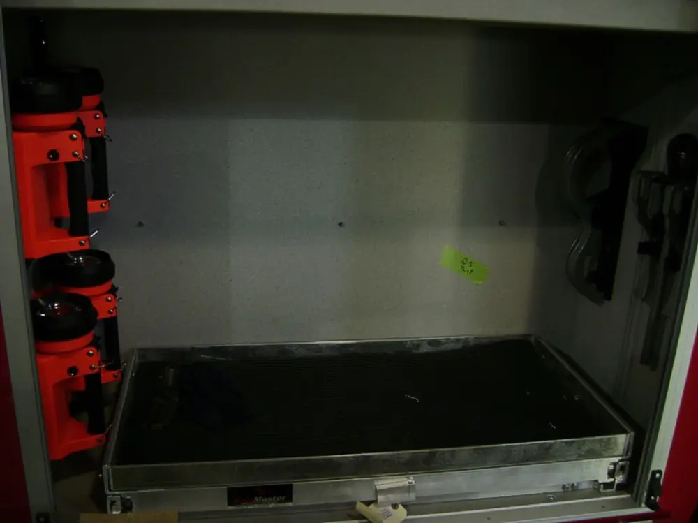 Exterior view of small fire truck showing cab, body compartments, and wheel/tire area.