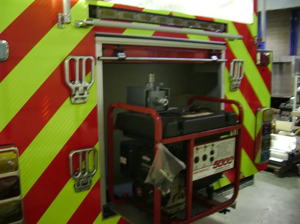 Exterior view of small fire truck showing cab, body compartments, and wheel/tire area.