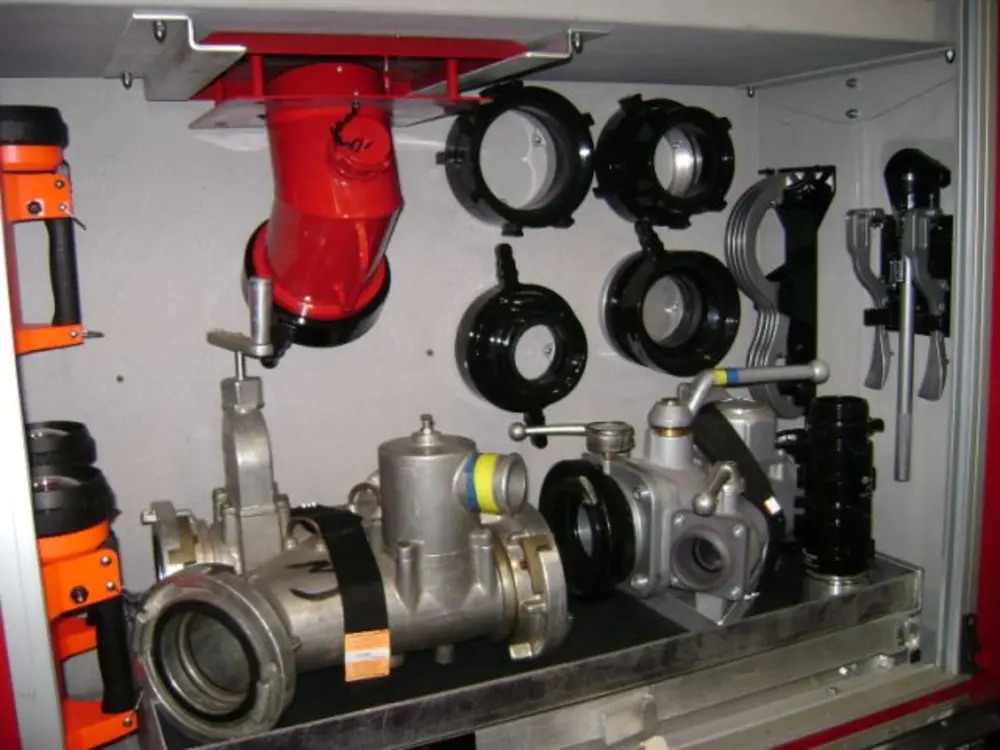 Exterior view of small fire truck showing cab, body compartments, and wheel/tire area.