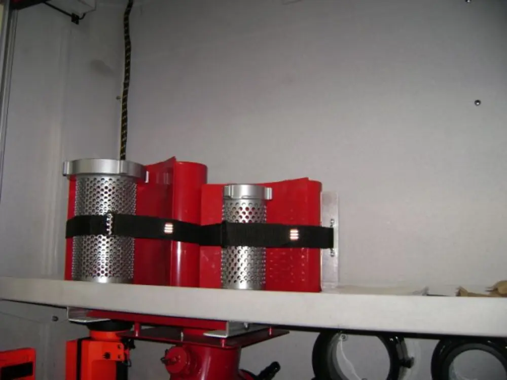 Exterior view of small fire truck showing cab, body compartments, and wheel/tire area.