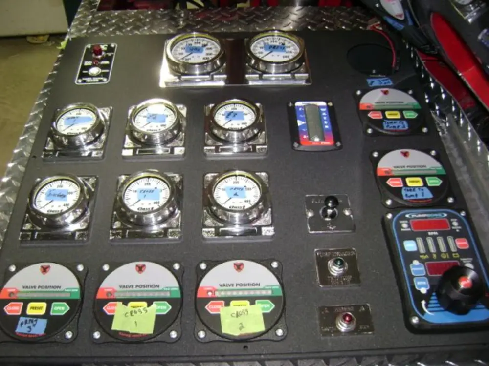 Exterior view of small fire truck showing cab, body compartments, and wheel/tire area.