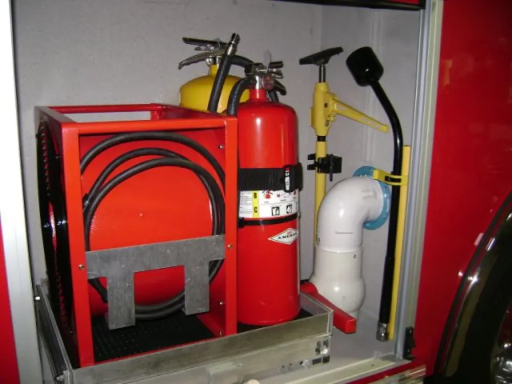 Exterior view of small fire truck showing cab, body compartments, and wheel/tire area.