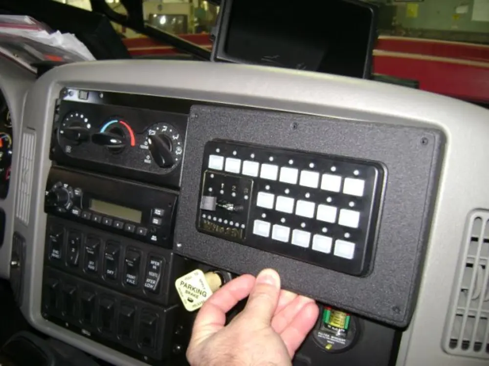 Exterior view of small fire truck showing cab, body compartments, and wheel/tire area.