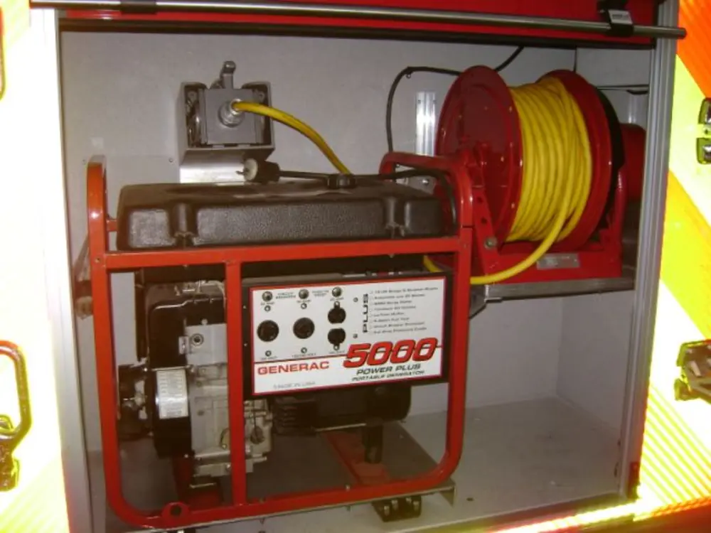 Exterior view of small fire truck showing cab, body compartments, and wheel/tire area.