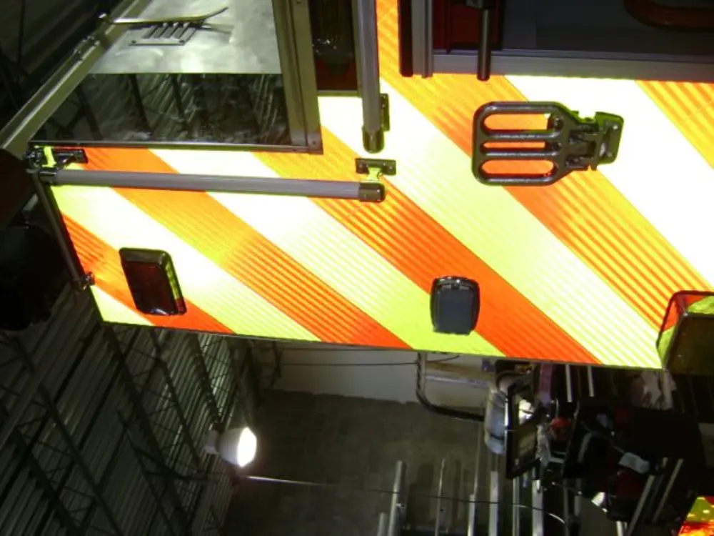 Exterior view of small fire truck showing cab, body compartments, and wheel/tire area.