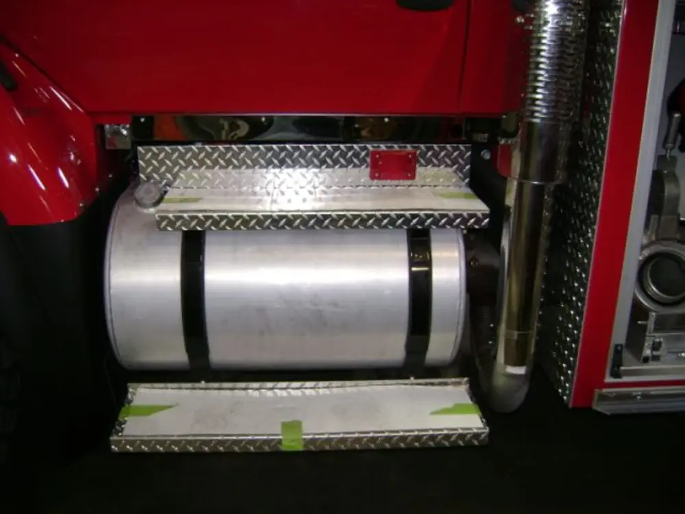 Exterior view of small fire truck showing cab, body compartments, and wheel/tire area.