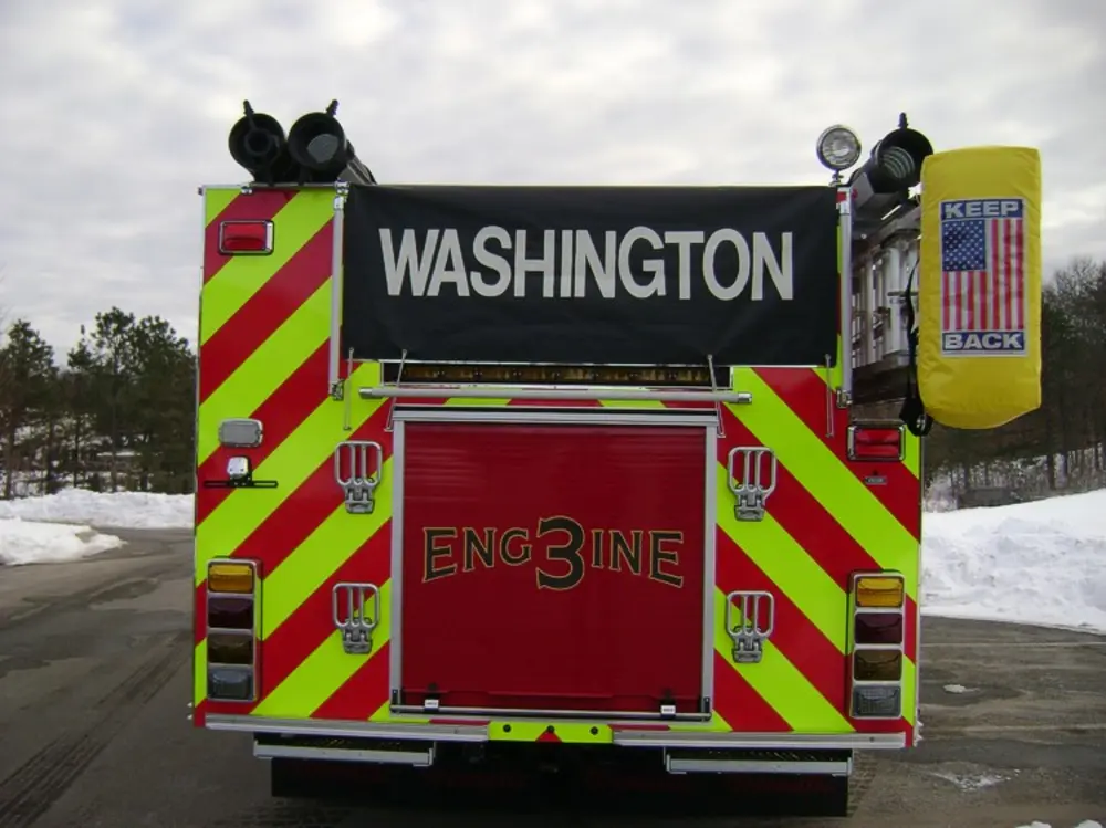 Exterior view of small fire truck showing cab, body compartments, and wheel/tire area.