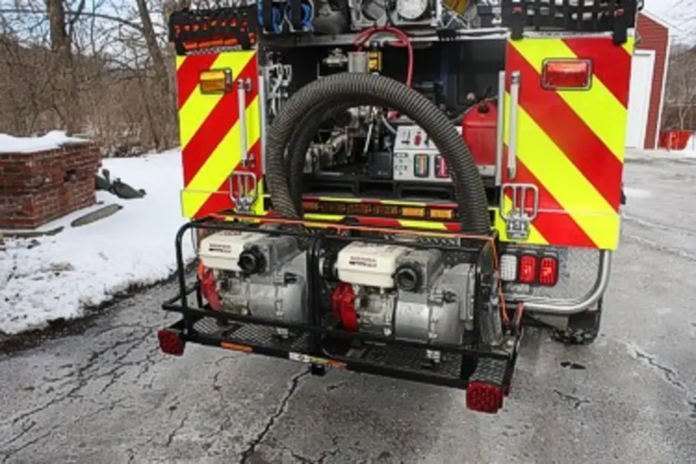 Exterior view of small fire truck showing cab, body compartments, and wheel/tire area.