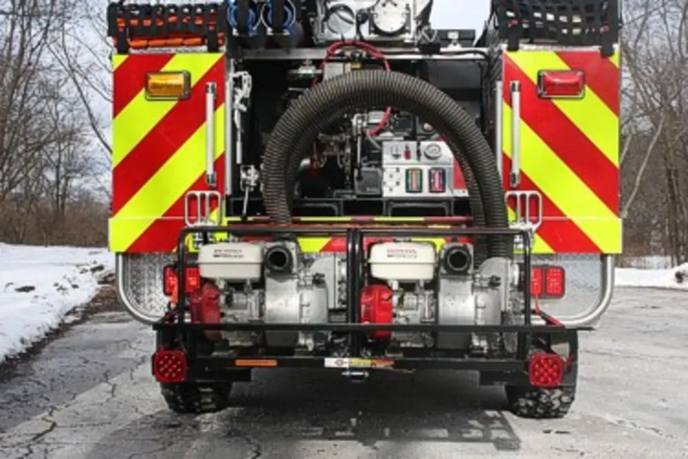 Exterior view of small fire truck showing cab, body compartments, and wheel/tire area.