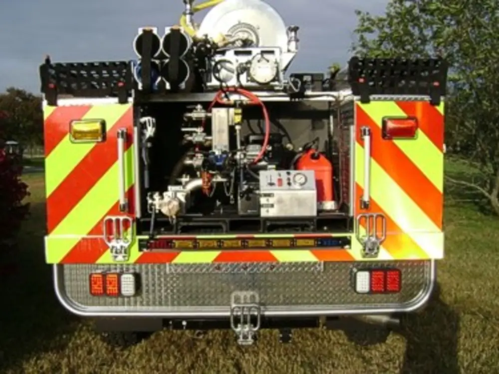 Exterior view of small fire truck showing cab, body compartments, and wheel/tire area.