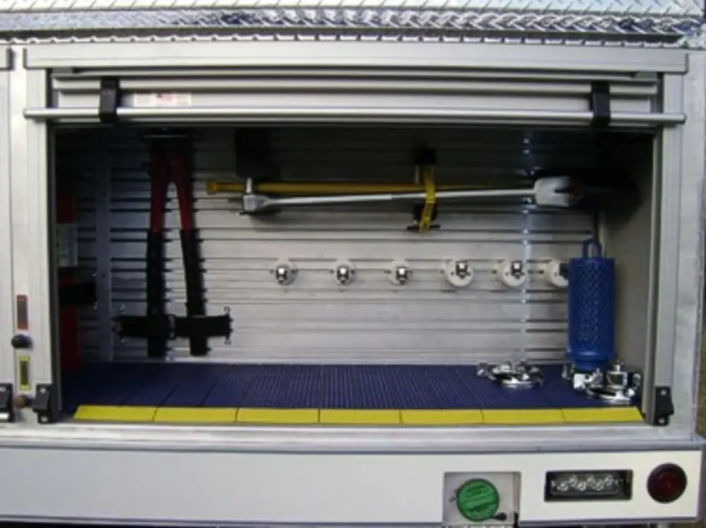 Exterior view of small fire truck showing cab, body compartments, and wheel/tire area.