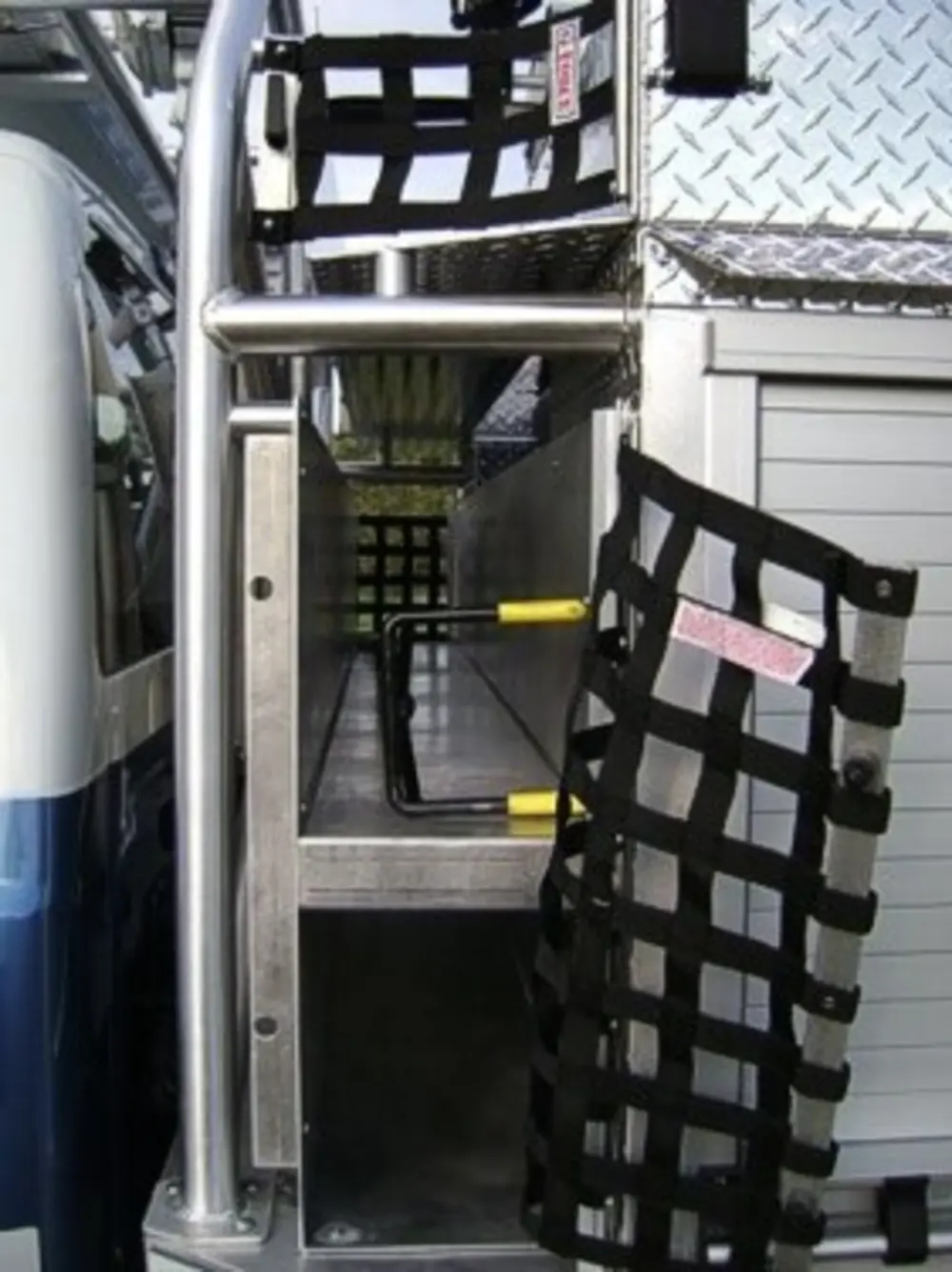 Exterior view of small fire truck showing cab, body compartments, and wheel/tire area.