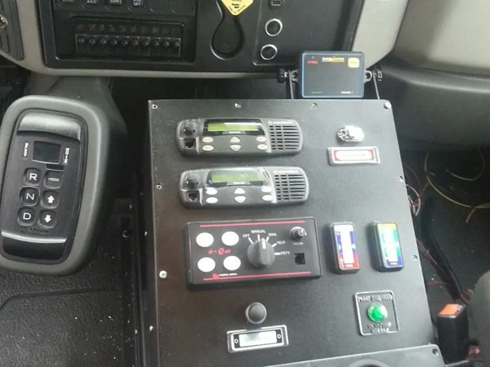 Exterior view of small fire truck showing cab, body compartments, and wheel/tire area.