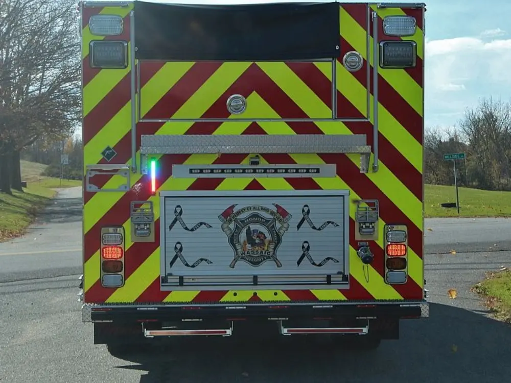 Exterior view of small fire truck showing cab, body compartments, and wheel/tire area.