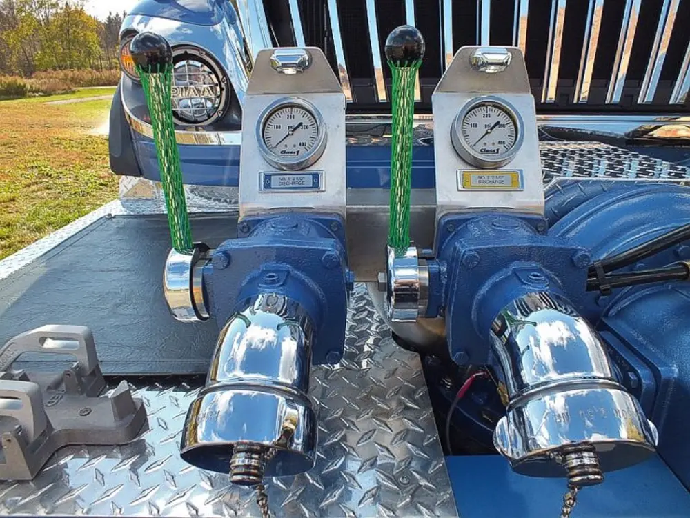 Exterior view of small fire truck showing cab, body compartments, and wheel/tire area.