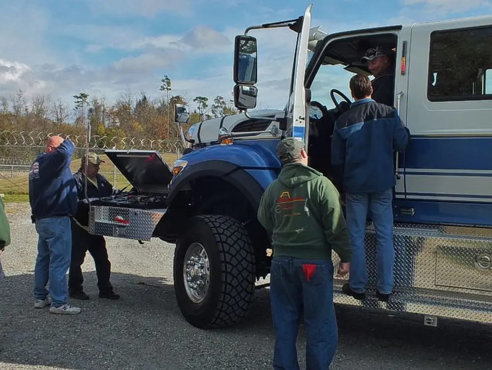 Exterior view of small fire truck showing cab, body compartments, and wheel/tire area.