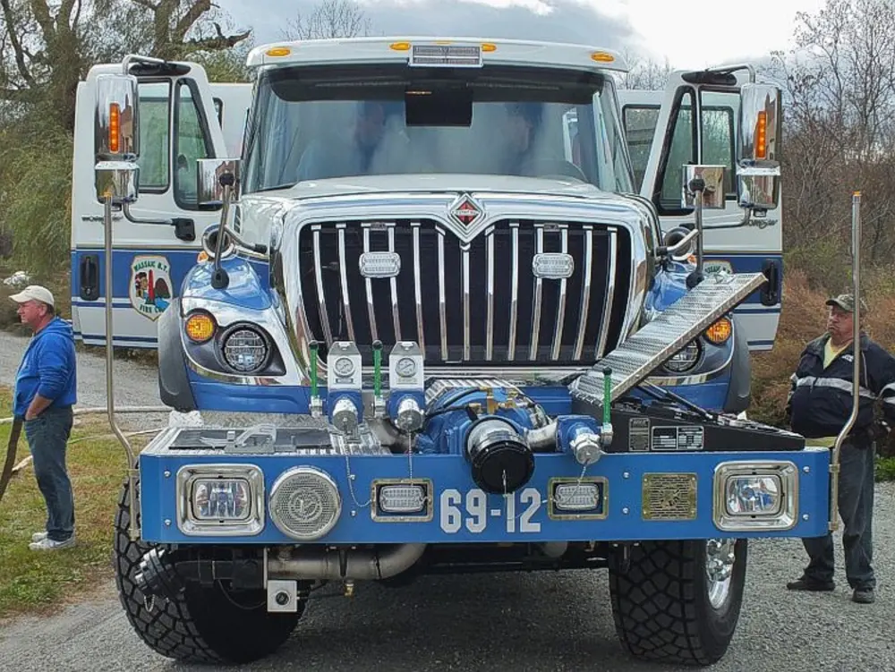 Exterior view of small fire truck showing cab, body compartments, and wheel/tire area.
