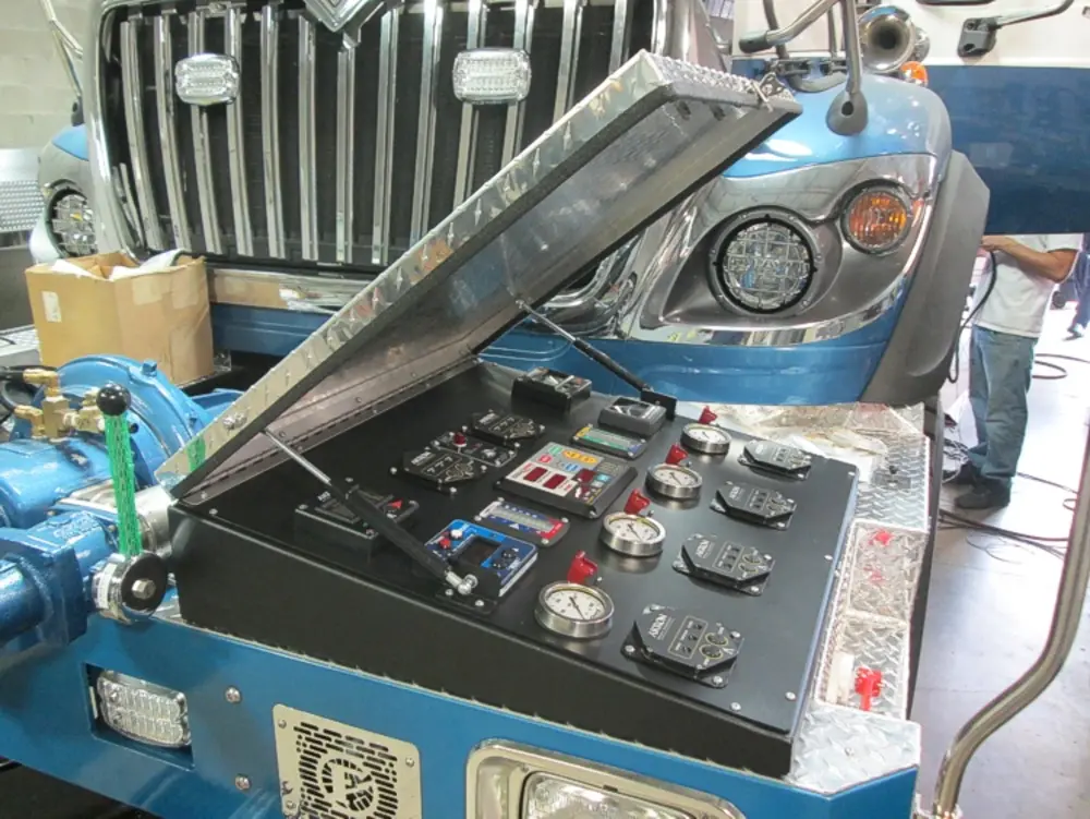 Exterior view of small fire truck showing cab, body compartments, and wheel/tire area.