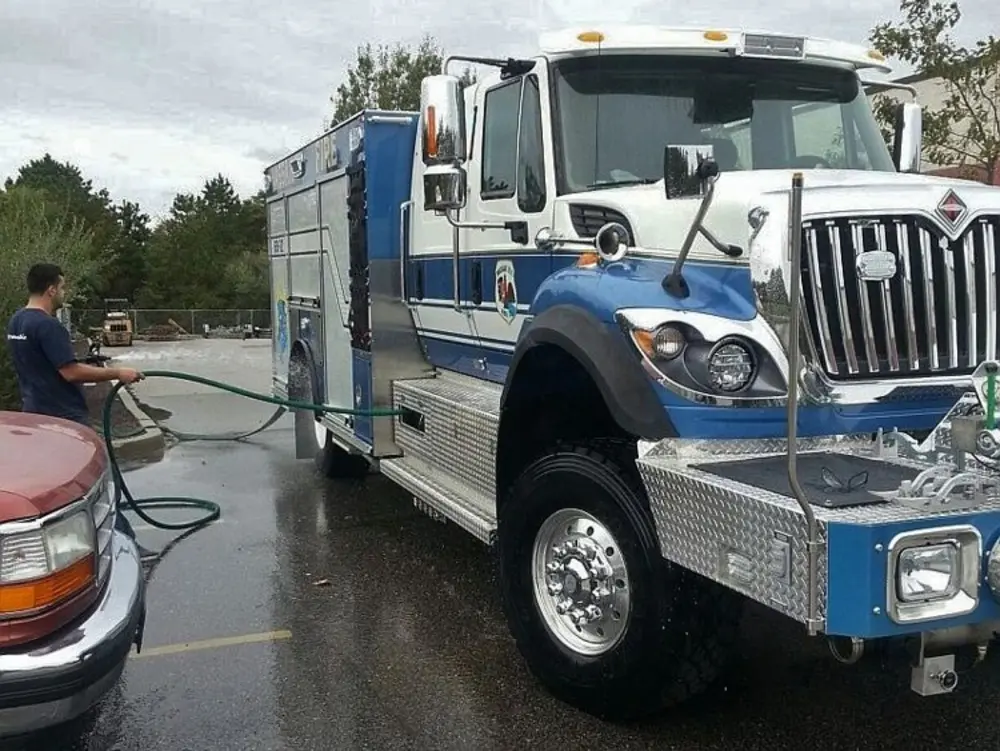 Exterior view of small fire truck showing cab, body compartments, and wheel/tire area.