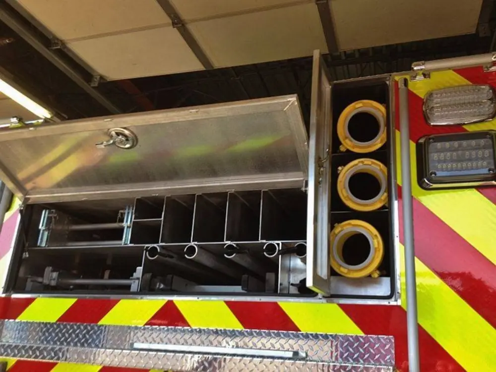 Exterior view of small fire truck showing cab, body compartments, and wheel/tire area.