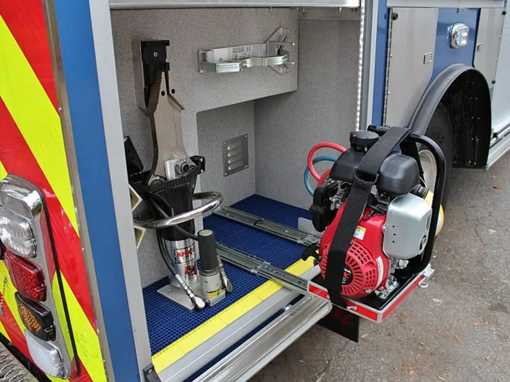 Exterior view of small fire truck showing cab, body compartments, and wheel/tire area.