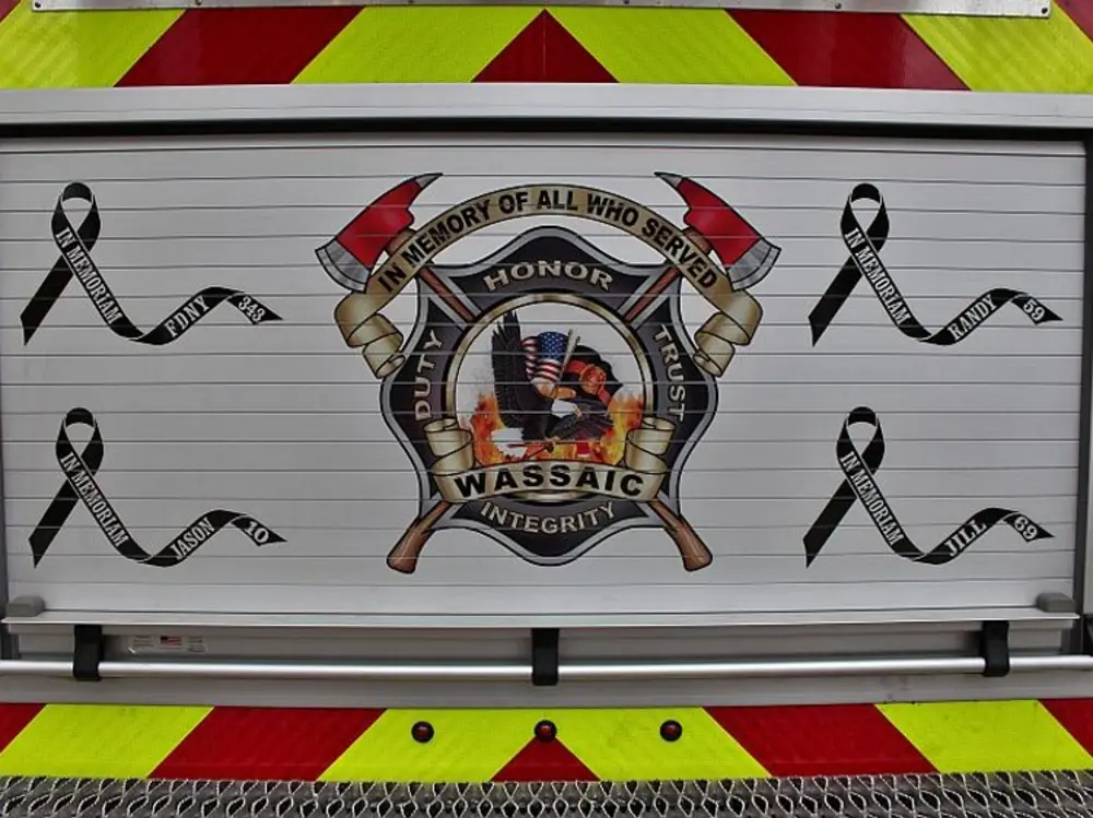 Exterior view of small fire truck showing cab, body compartments, and wheel/tire area.