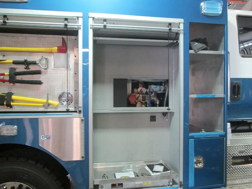 Exterior view of small fire truck showing cab, body compartments, and wheel/tire area.