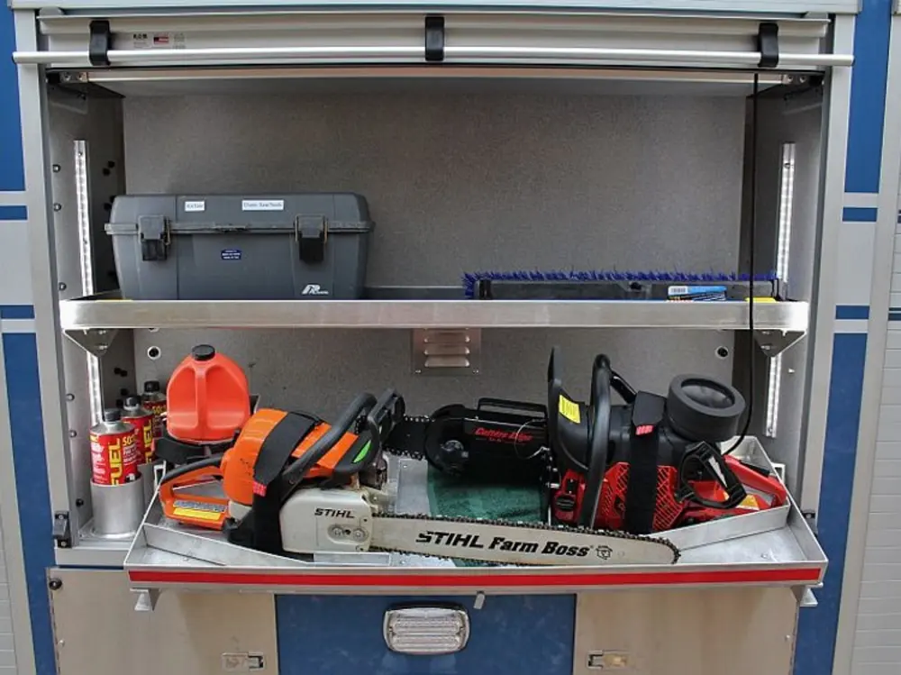 Exterior view of small fire truck showing cab, body compartments, and wheel/tire area.