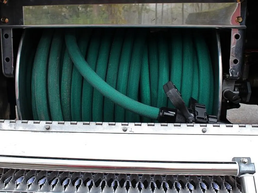 Exterior view of small fire truck showing cab, body compartments, and wheel/tire area.