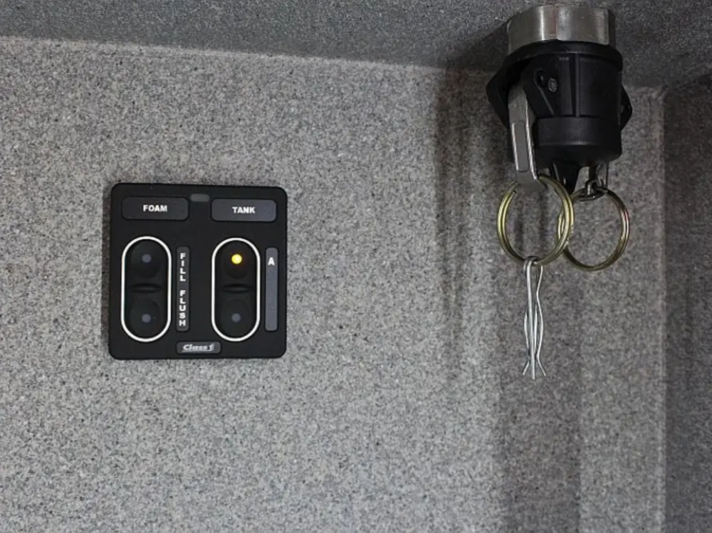 Exterior view of small fire truck showing cab, body compartments, and wheel/tire area.