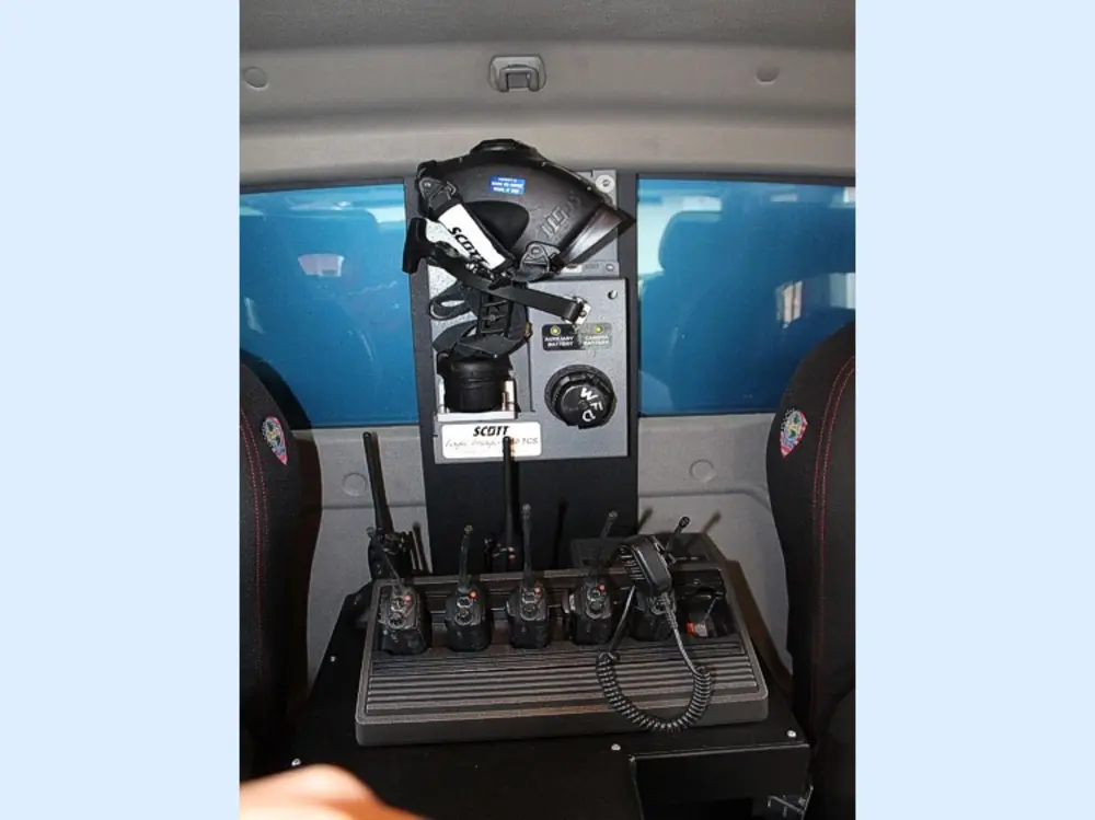 Exterior view of small fire truck showing cab, body compartments, and wheel/tire area.