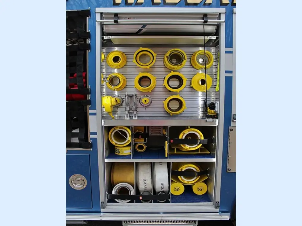 Exterior view of small fire truck showing cab, body compartments, and wheel/tire area.