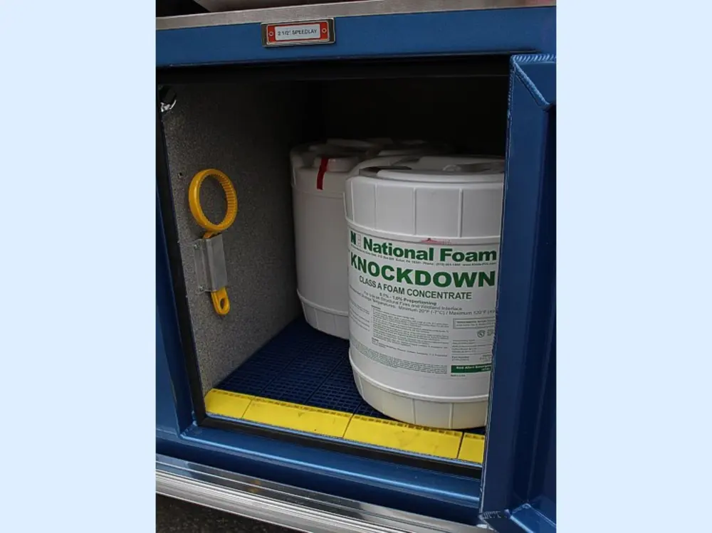 Exterior view of small fire truck showing cab, body compartments, and wheel/tire area.