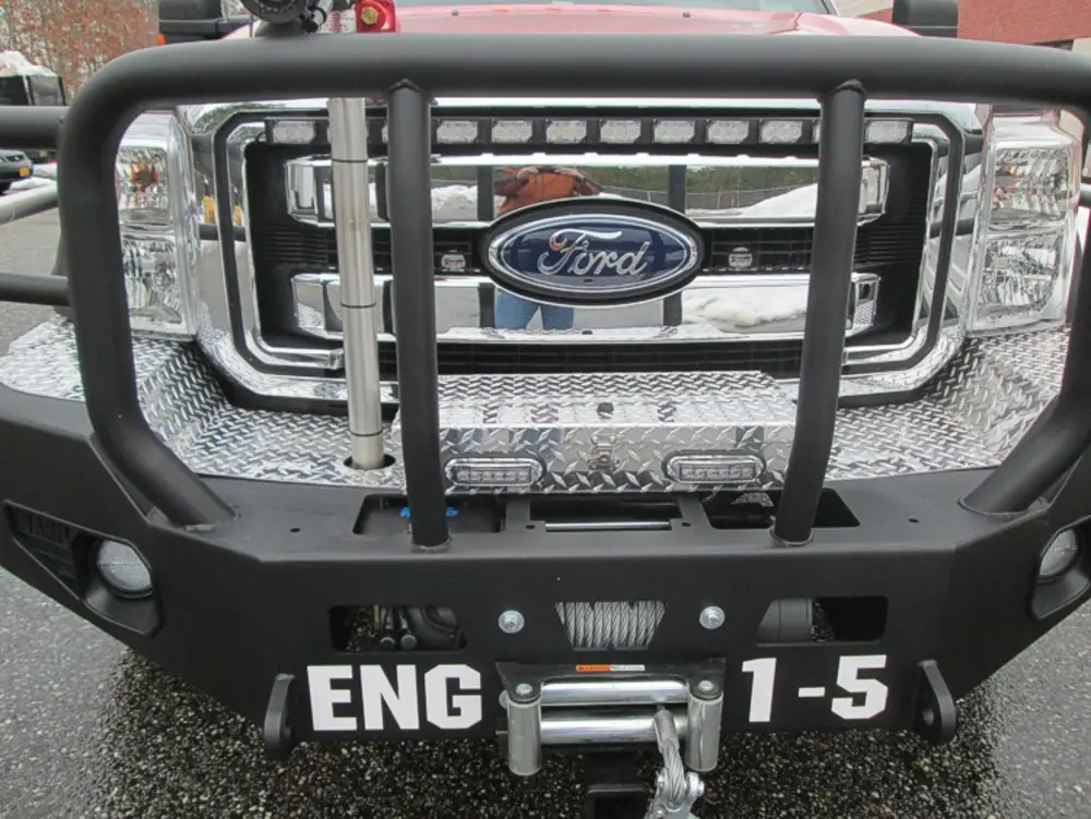 Exterior view of small fire truck showing cab, body compartments, and wheel/tire area.