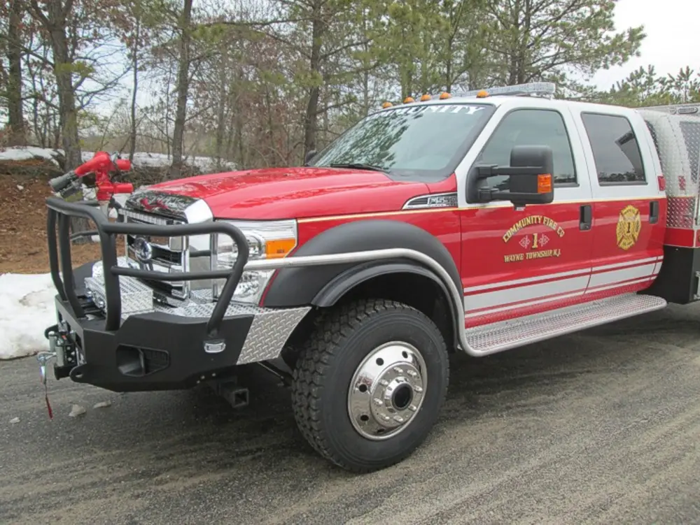 Exterior view of small fire truck showing cab, body compartments, and wheel/tire area.