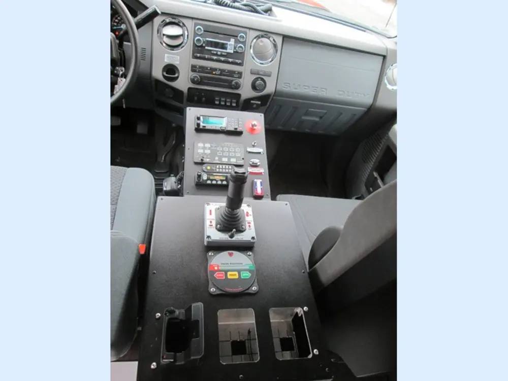 Exterior view of small fire truck showing cab, body compartments, and wheel/tire area.