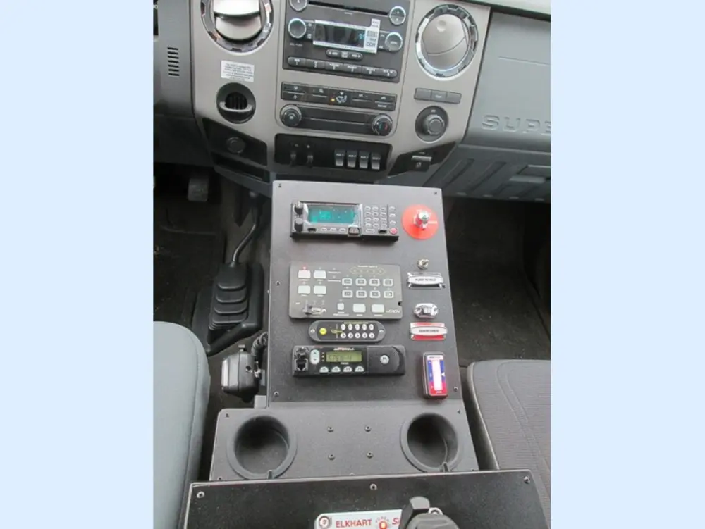 Exterior view of small fire truck showing cab, body compartments, and wheel/tire area.