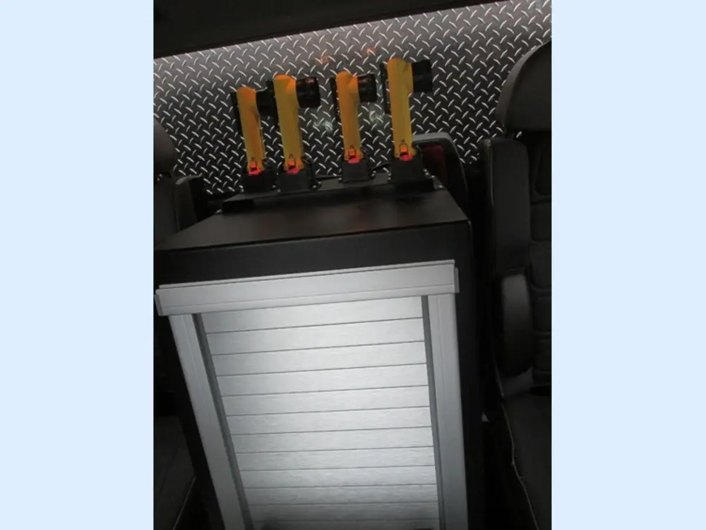 Exterior view of small fire truck showing cab, body compartments, and wheel/tire area.