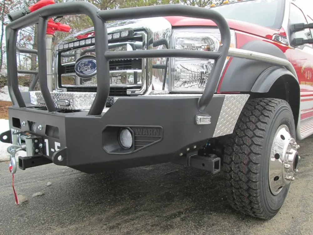 Exterior view of small fire truck showing cab, body compartments, and wheel/tire area.