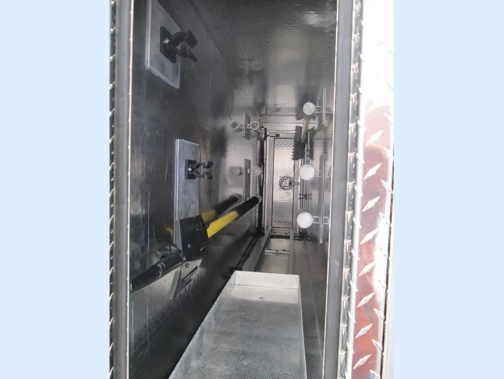 Exterior view of small fire truck showing cab, body compartments, and wheel/tire area.