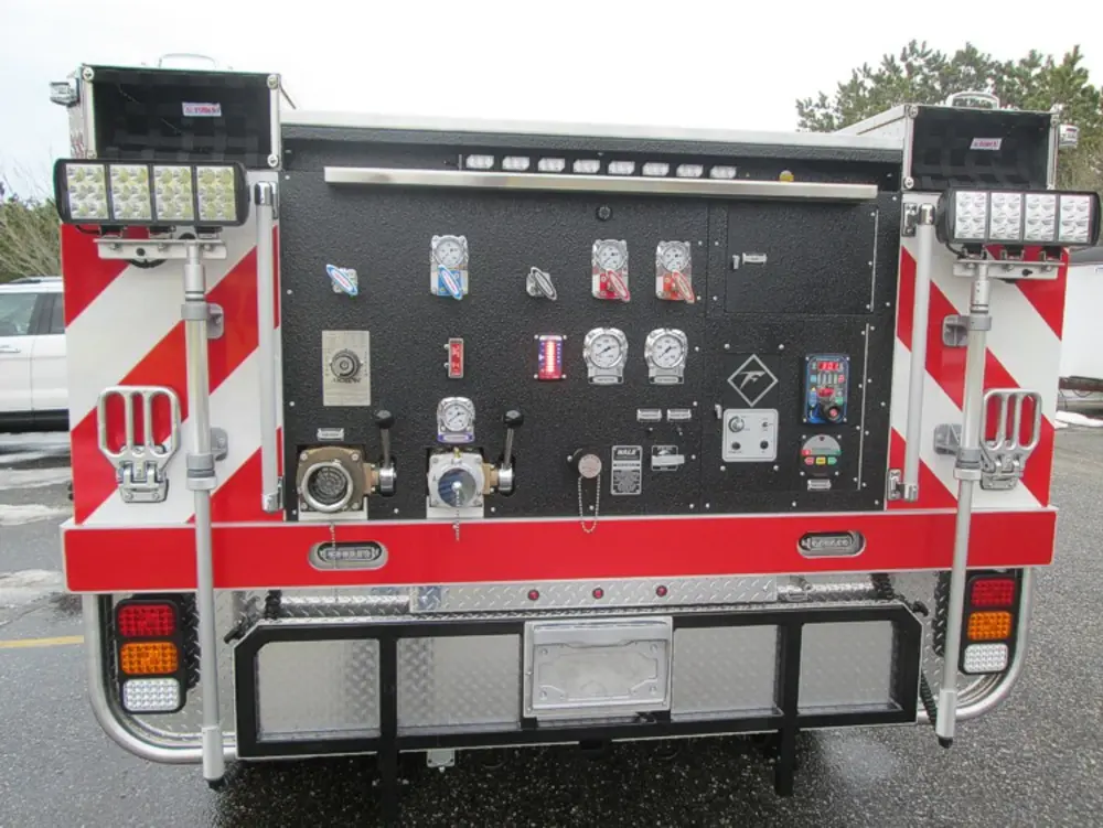 Exterior view of small fire truck showing cab, body compartments, and wheel/tire area.