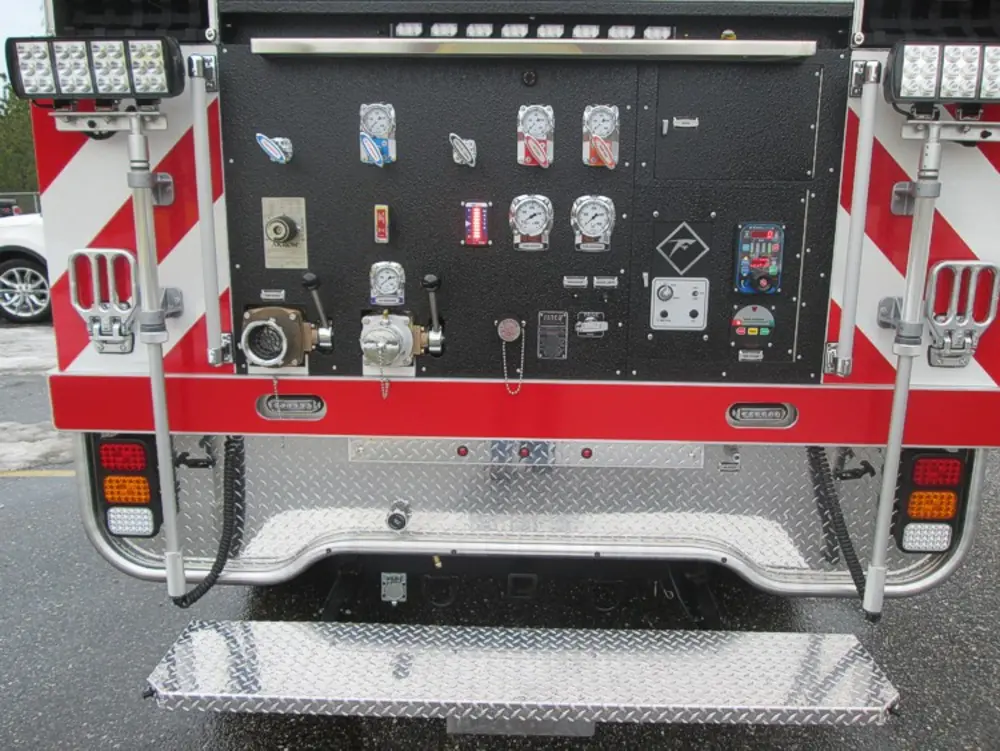 Exterior view of small fire truck showing cab, body compartments, and wheel/tire area.