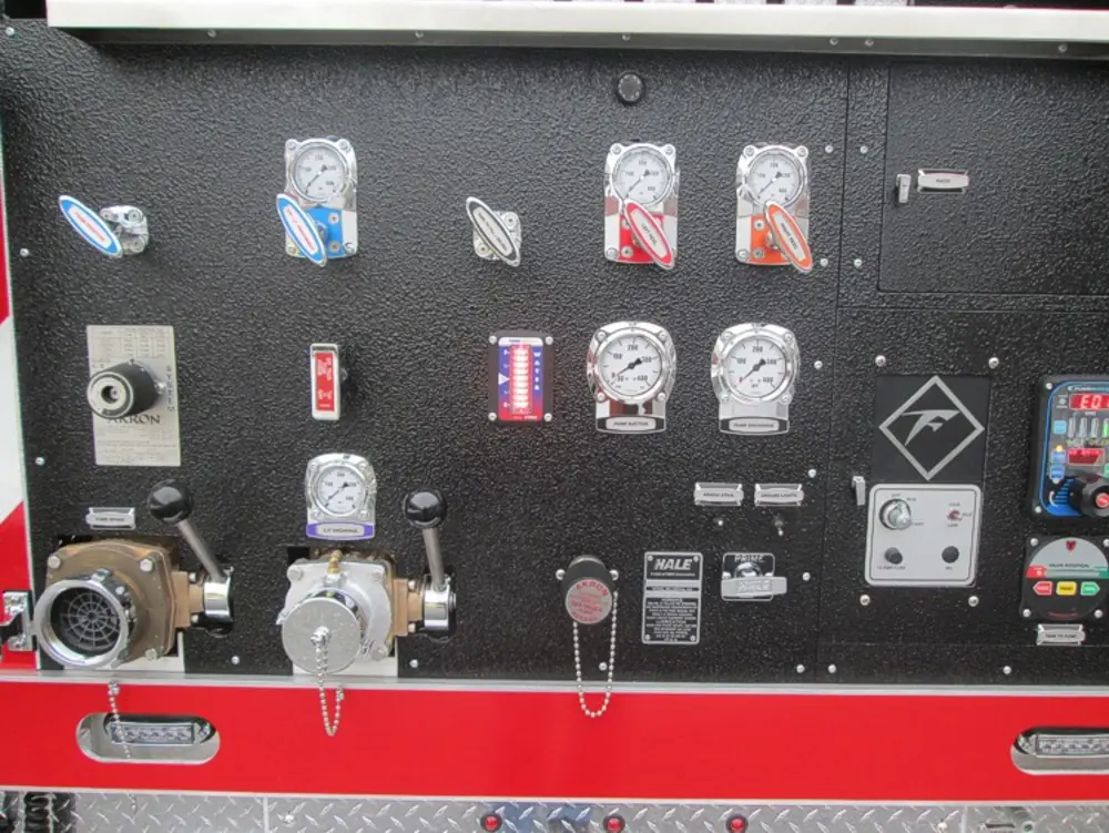 Exterior view of small fire truck showing cab, body compartments, and wheel/tire area.