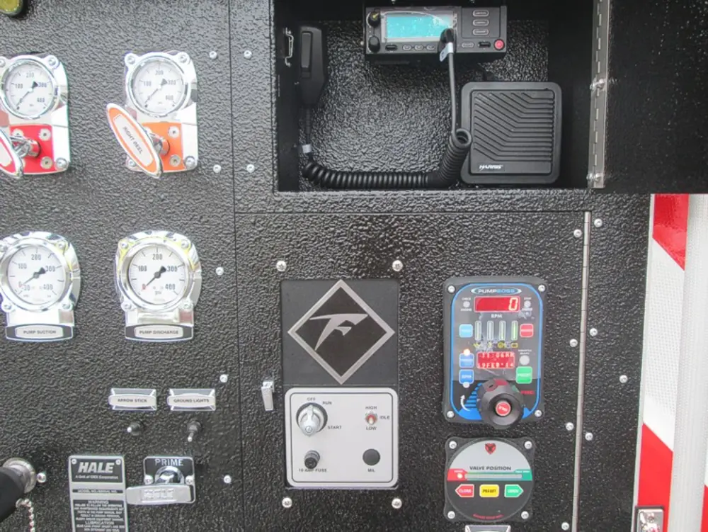 Exterior view of small fire truck showing cab, body compartments, and wheel/tire area.