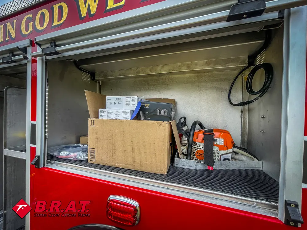 Open side compartment with shelf and stored chainsaw and equipment.