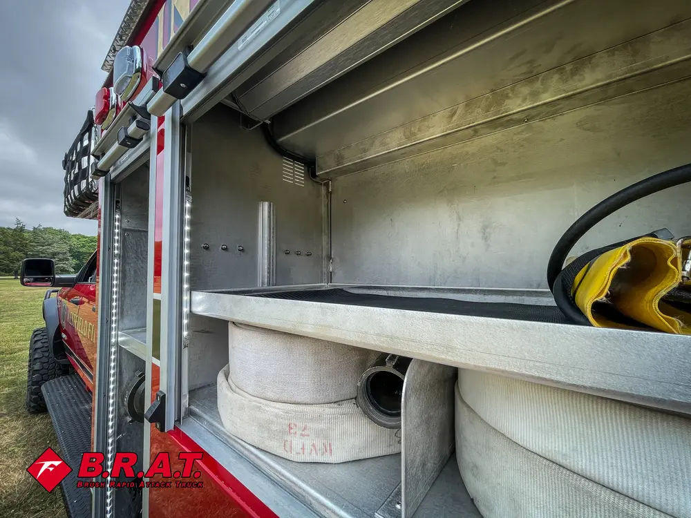 Open side compartment from rear angle with shelf and hose storage.