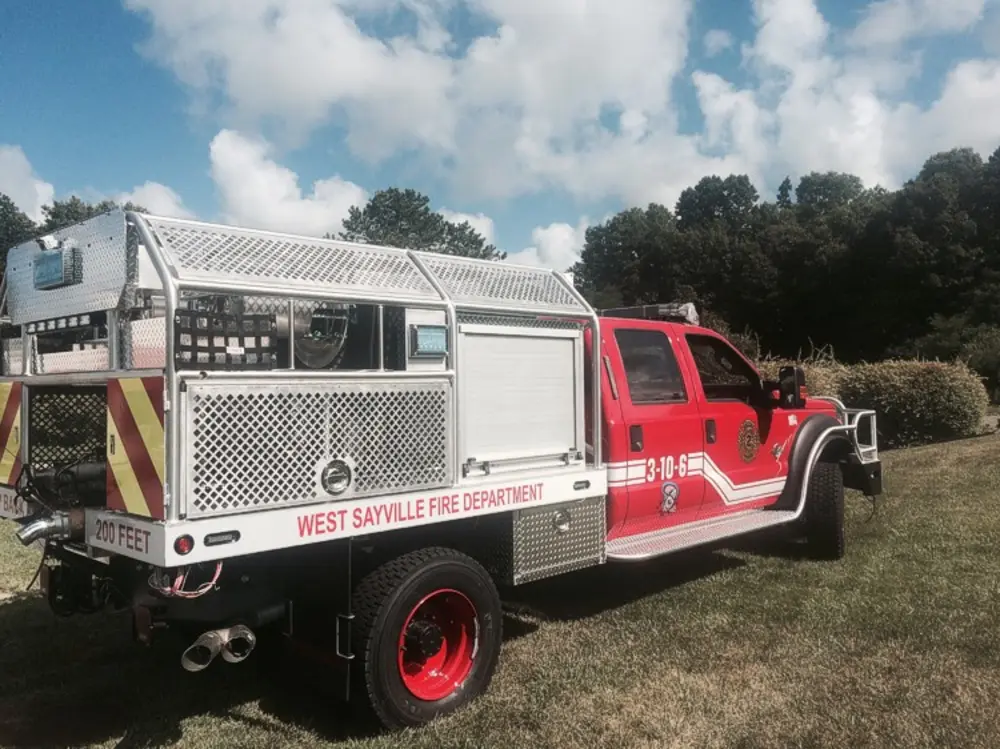 Exterior view of small fire truck showing cab, body compartments, and wheel/tire area.
