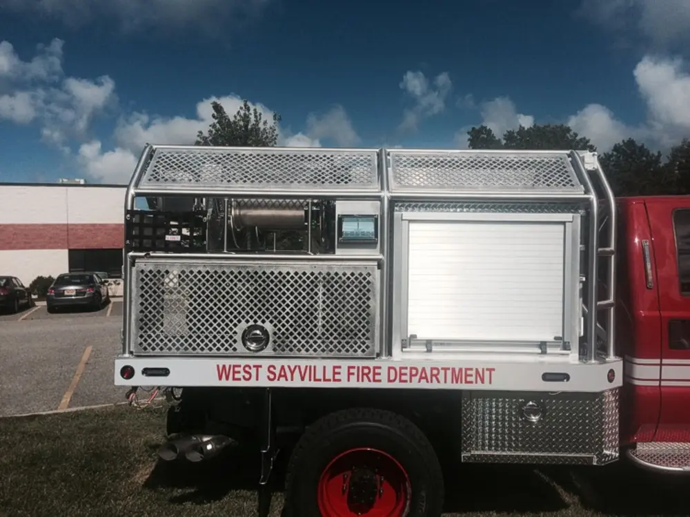 Exterior view of small fire truck showing cab, body compartments, and wheel/tire area.