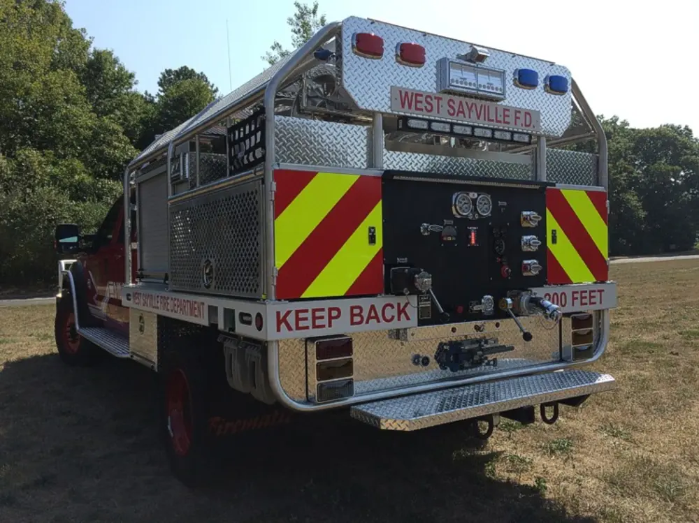 Exterior view of small fire truck showing cab, body compartments, and wheel/tire area.